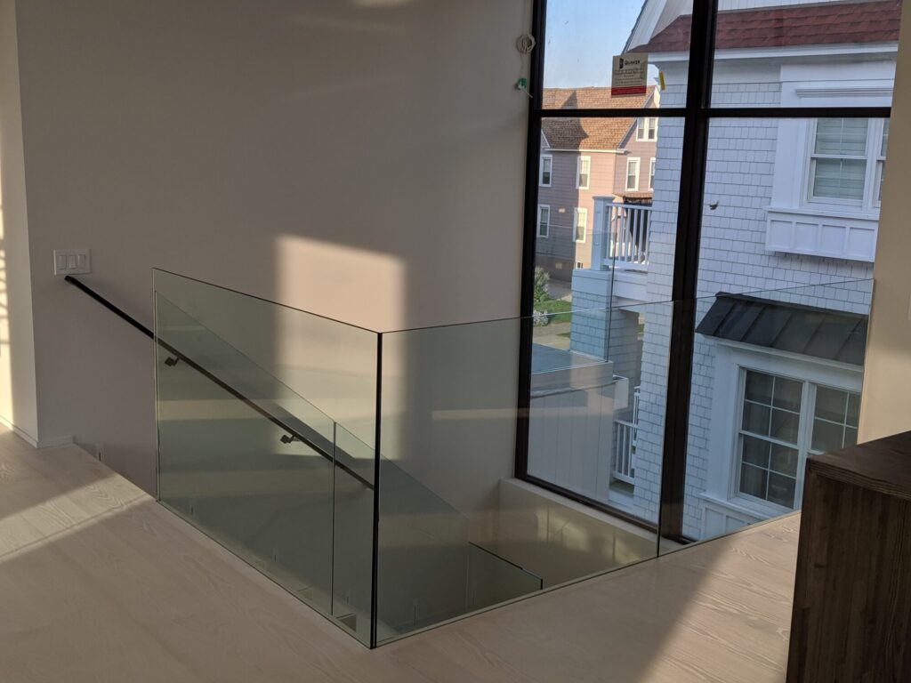 Modern zig zag stair with glass panels and satin black metal rails, photo 1 of 9