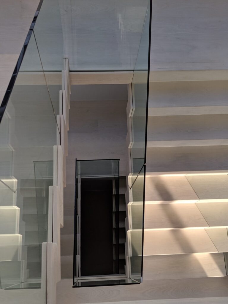 Modern zig zag stair with glass panels and satin black metal rails, photo 3 of 9
