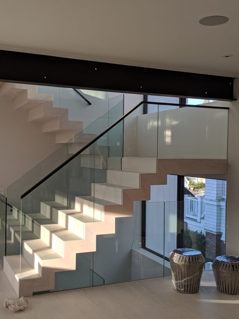 Modern zig zag stair with glass panels and satin black metal rails, photo 4 of 9