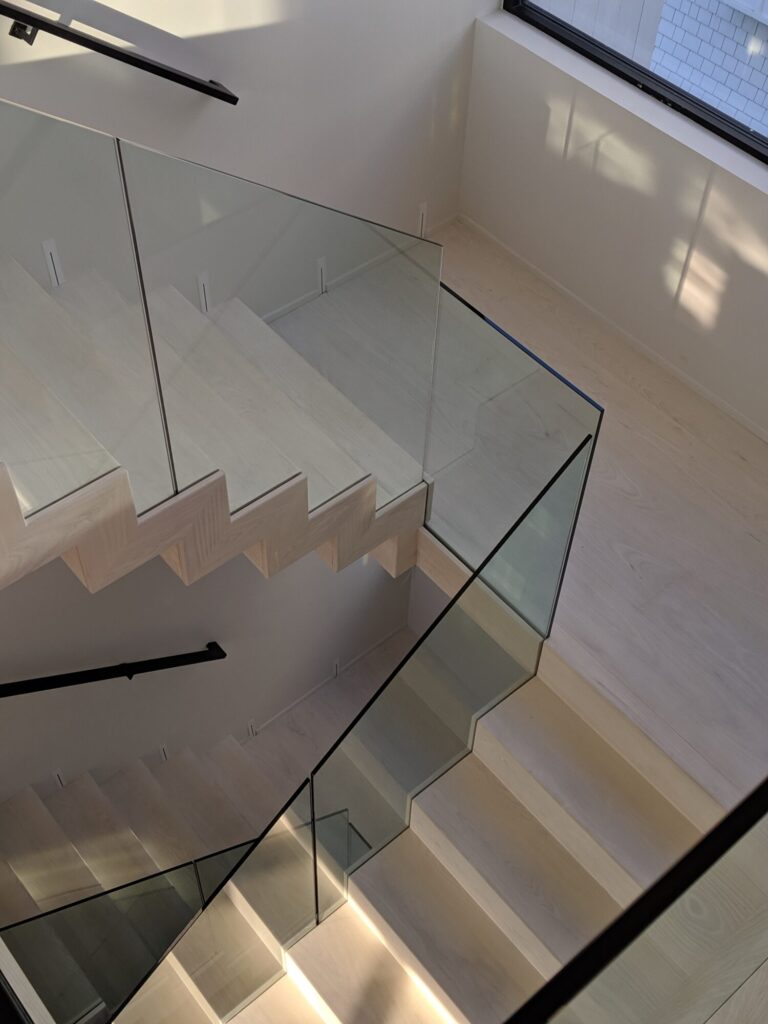 Modern zig zag stair with glass panels and satin black metal rails, photo 6 of 9