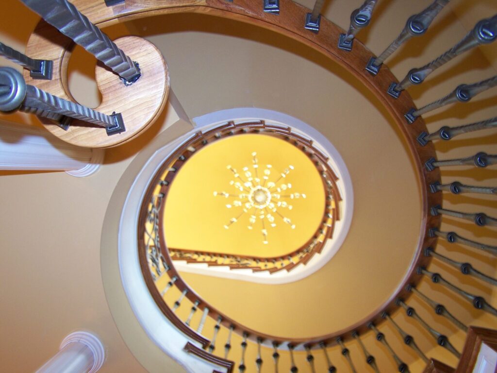 Traditional curved multi level staircase with iron balustrade: Brazilian cherry treads and handrails with tuscany iron. CNC tangent handrails, photo 15 of 18