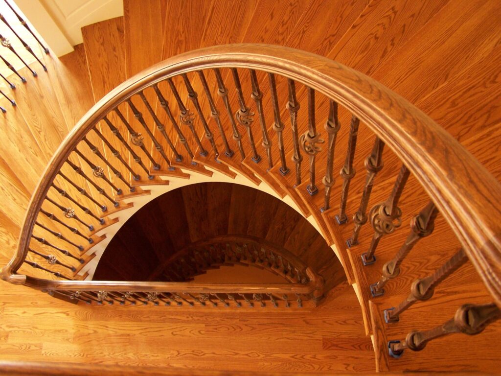 Traditional curved staircase with iron balustrade: Red oak treads and handrail, photo 11 of 11
