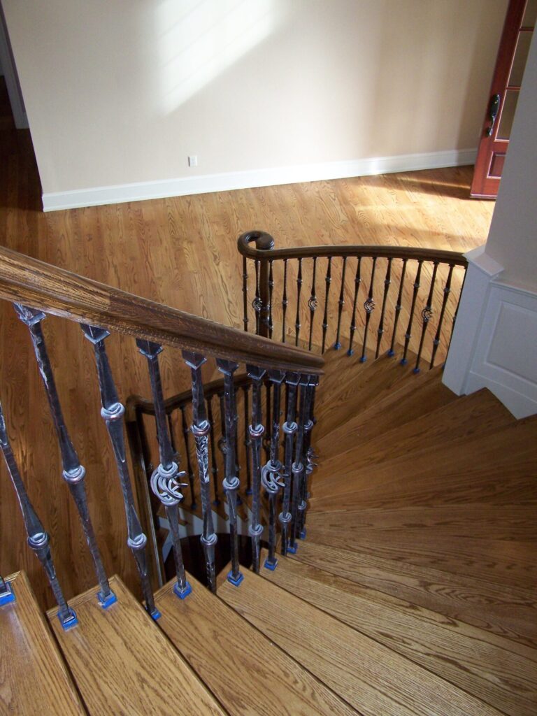 Traditional curved staircase with iron balustrade: Red oak treads and handrail, photo 9 of 11
