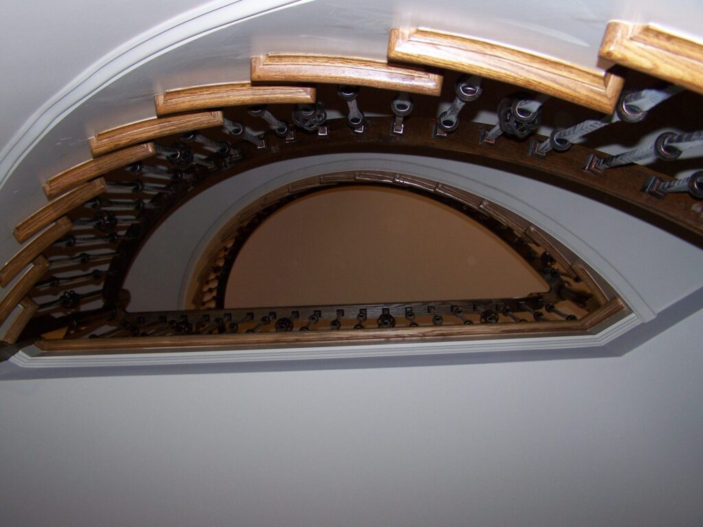 Traditional curved staircase with iron balustrade: Red oak treads and handrail, photo 4 of 11