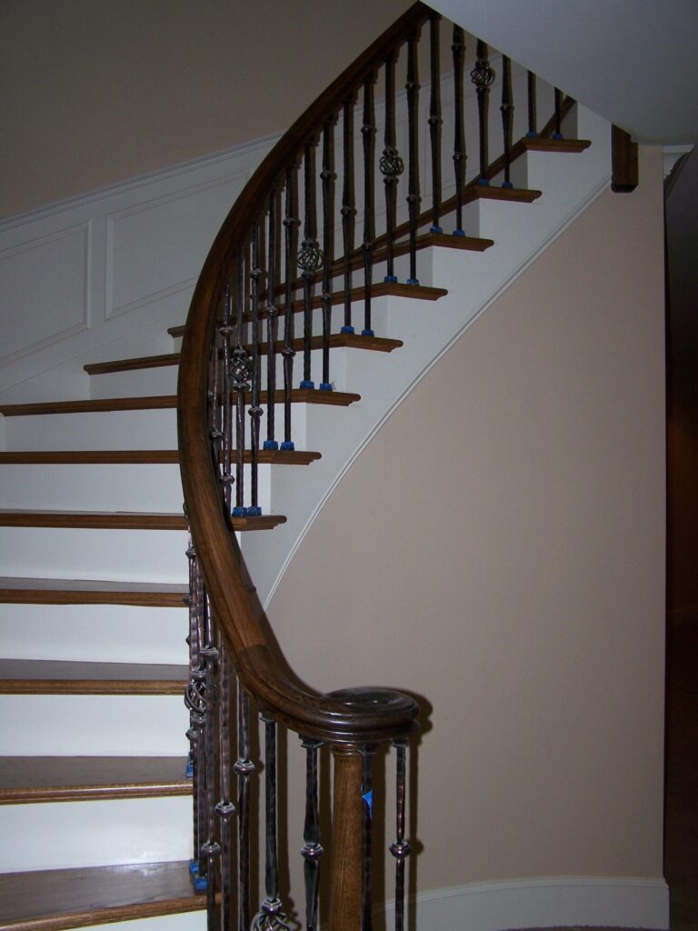 Traditional curved staircase with iron balustrade: Red oak treads and handrail, photo 3 of 11