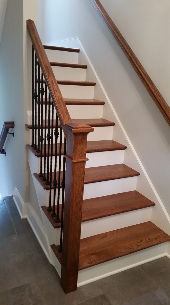 White oak square newel with simple cap and neck detail: Hammered rustic iron balustrade. Upper Makefield, PA, photo 1 of 17
