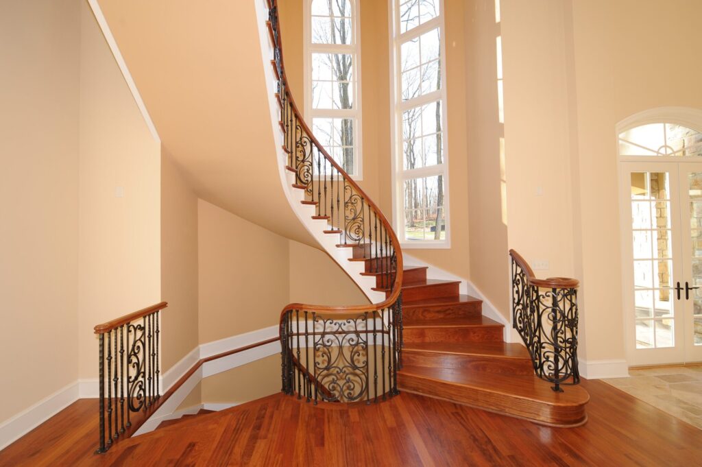 Traditional curved multi level staircase with iron balustrade: Brazilian cherry treads and handrails with tuscany iron. CNC tangent handrails, photo 11 of 18