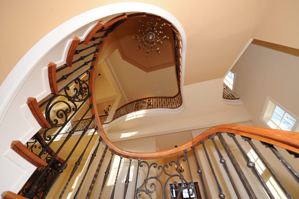 Traditional curved multi level staircase with iron balustrade: Brazilian cherry treads and handrails with tuscany iron. CNC tangent handrails, photo 9 of 18