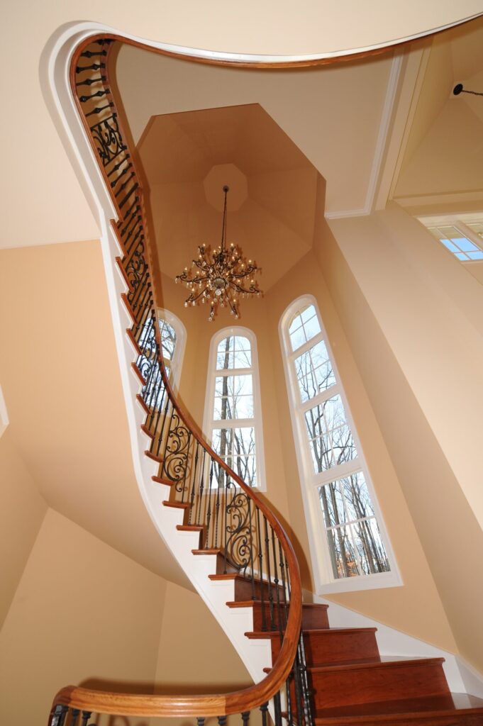 Traditional curved multi level staircase with iron balustrade: Brazilian cherry treads and handrails with tuscany iron. CNC tangent handrails, photo 8 of 18