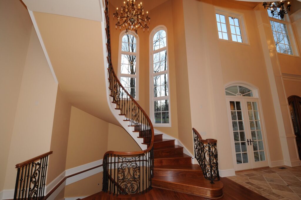 Traditional curved multi level staircase with iron balustrade: Brazilian cherry treads and handrails with tuscany iron. CNC tangent handrails, photo 6 of 18