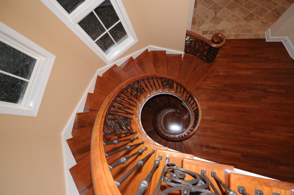 Traditional curved multi level staircase with iron balustrade: Brazilian cherry treads and handrails with tuscany iron. CNC tangent handrails, photo 5 of 18