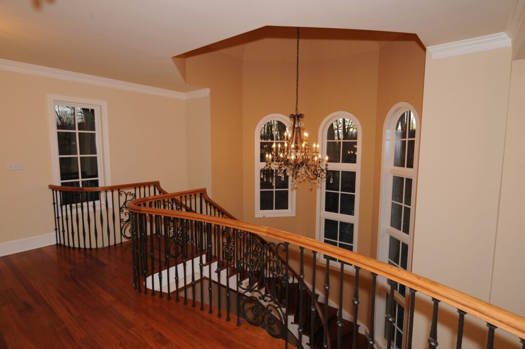Traditional curved multi level staircase with iron balustrade: Brazilian cherry treads and handrails with tuscany iron. CNC tangent handrails, photo 2 of 18